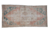 Distressed vintage Oushak rug, faded coral field, dusty teal spandrels, floral medallion.