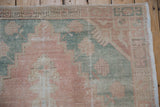 Distressed vintage Oushak rug detail showing worn coral, dusty teal pile and foundation.