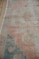 Vintage distressed Oushak rug showing worn coral pile, geometric border, and foundation.