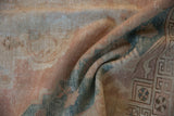Distressed Oushak rug's geometric border, showcasing worn coral, dusty teal, and beige tones.