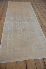 Distressed pile texture with faded dusty gold and seafoam green medallion motifs on Oushak runner.