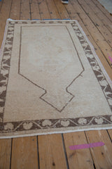 Distressed pile of a vintage Oushak rug, beige field, brown geometric border.