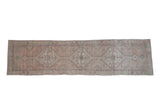 Distressed Oushak runner with faded pale rose, ivory, and turquoise geometric medallions.