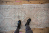 Distressed vintage Oushak runner detail showcasing faded pale rose and ivory geometric patterns.
