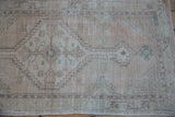 Distressed vintage Oushak runner with geometric floral motifs in pale rose and ivory.