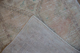Vintage distressed Oushak runner's worn pile with pale hues and visible hand-knotted foundation.