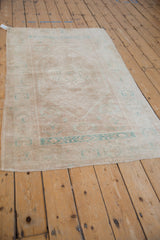 Distressed Oushak rug's dog-eared corner, secured overcast stitch, and side selvage.