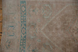 Time-softened dusty mauve and muted turquoise geometric motifs on the distressed vintage Oushak pile.