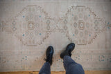 Distressed vintage Oushak rug runner; ivory field with pale turquoise guls and coffee brown contours.