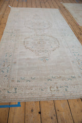 Distressed Oushak runner detail: serrated medallion, pinwheel guls, ivory, pale brown, and dusty blue.