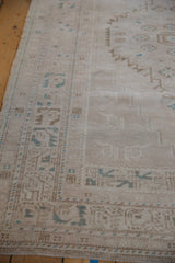 Ivory, coffee brown, and dusty turquoise stylized patterns with serrated contours on this distressed Oushak rug.