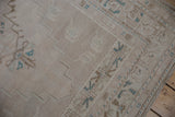 Distressed vintage Oushak rug showing even wear, pale ivory field, and dusty turquoise motifs.