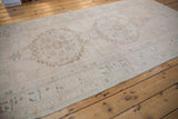 Vintage distressed Oushak runner's textured pile, serrated medallion, and border in ivory, brown, turquoise.