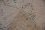 Distressed Oushak rug corner showing worn pile and hand-knotted reverse.