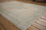 Distressed vintage Oushak carpet showing low pile texture in muted cream and seafoam green.