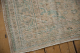 Distressed vintage Oushak rug corner with aged cream, seafoam green Rococo patterns, fringe.