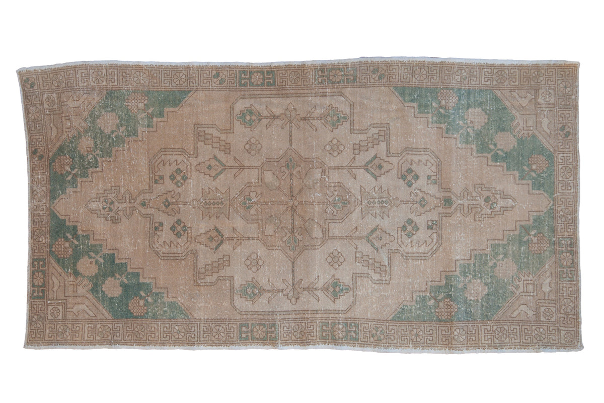 Vintage Oushak rug runner with a distressed geometric medallion in pale turquoise green and sand tones.