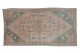 Vintage Oushak rug runner with a distressed geometric medallion in pale turquoise green and sand tones.