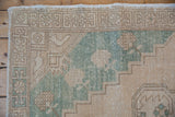 Geometric border and evenly worn low pile on the corner of a vintage Oushak rug.