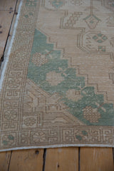Evenly worn pile of a distressed Oushak rug corner, showing the intact selvage and geometric border.