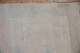 Faded ivory vintage Oushak rug pile with distressed pale mauve and seafoam floral designs.
