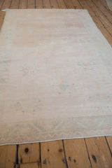 Faint floral details on the evenly worn pile of a distressed ivory Oushak rug.