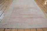 Distressed Oushak rug texture with muted pink pile, abrash, and side cord selvage.