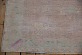Distressed Oushak rug pile texture showing even wear, intact original selvage, ivory, green, and mauve.