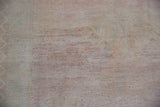 Muted tones and visible hand knot texture on the back of the distressed Oushak rug.