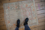 Distressed vintage Oushak rug with textural beige, soft pink, and tangerine prayer motif.