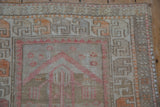 Textured geometric border of a distressed Oushak rug in pale ruby red, tangerine, and oxidized silver.