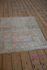 Distressed Oushak rug with faded tangerine geometric border and low pile texture.