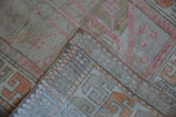 Distressed Oushak rug's folded corner shows low pile, woven foundation, and neat side selvage.