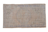 Vintage distressed Oushak rug with a faded medallion design in soft ivory, beige, and denim blue tones.