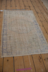 Angled view of a distressed Oushak rug, showing its overall worn texture and faded medallion.