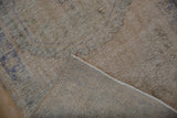 Woven foundation and distressed, low-pile texture of a vintage Turkish Oushak rug corner.