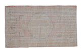 Distressed hand-knotted Oushak rug with faded roundel medallion in soft rose and pale gold.