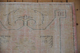 Distressed Oushak rug corner detail, revealing worn pile, dusty gold, and dusty rose selvage.