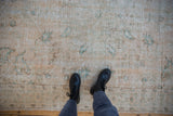 Distressed Oushak rug texture, faded cream, dusty seafoam green, foundation showing through.