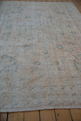 Distressed Oushak rug pile reveals mostly even wear, foundation, and faded cream, seafoam motifs.