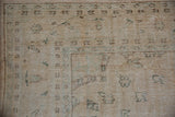 Distressed vintage Oushak carpet pile, revealing foundation wear and muted cream-green patterns.