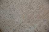 Distressed Oushak rug showing worn pile to foundation with faded cream, brown, and seafoam green patterns.
