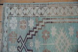 Distressed Oushak rug close-up showing even wear, mint green field, and stepped border pattern.
