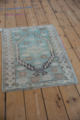 Corner detail of distressed Oushak rug with mint green pile, abrashes, and secured fringe.