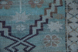 Mint green and aubergine stepped geometric pattern detail on a distressed Oushak rug.