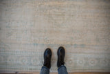 Close-up of distressed Vintage Oushak carpet, showing worn ivory pile and soft teal motifs.