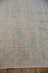 Distressed Oushak pile with softened ivory and dusty teal floral motifs.