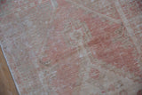 Close-up of distressed texture and faded blush pink, ivory tones of vintage Oushak.