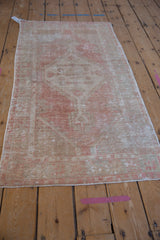 Hand knotted Oushak runner with distressed texture, showing faded blush, ivory medallion, and spandrels.