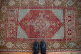 Distressed Anatolian rug border: cherry red, bronze, mint green floral motifs with even wear.